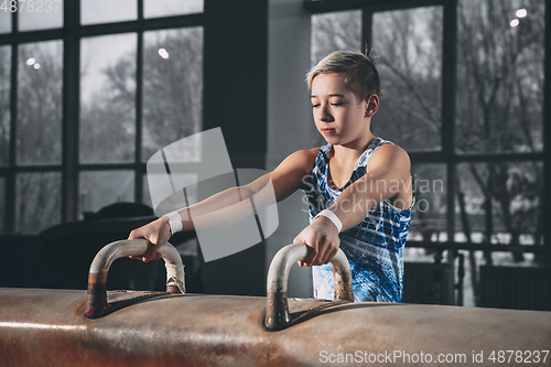 Image of Little male gymnast training in gym, flexible and active. Caucasian fit little boy, athlete in sportswear practicing in exercises for strength, balance.