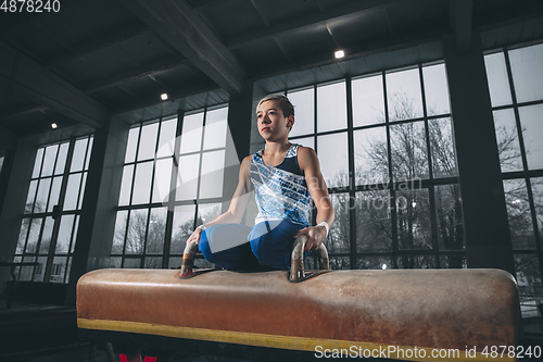 Image of Little male gymnast training in gym, flexible and active. Caucasian fit little boy, athlete in sportswear practicing in exercises for strength, balance.