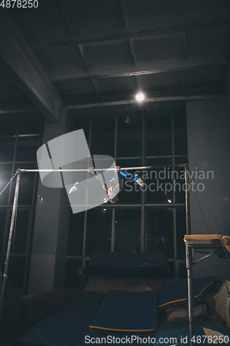 Image of Little male gymnast training in gym, flexible and active. Caucasian fit little boy, athlete in sportswear practicing in exercises for strength, balance.