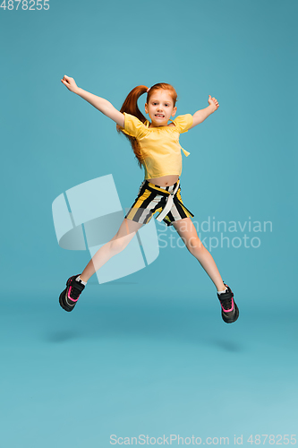 Image of Happy caucasian little girl isolated on blue studio background. Looks happy, cheerful, sincere. Copyspace. Childhood, education, emotions concept