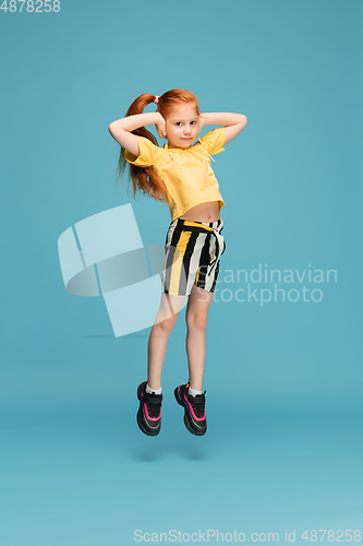 Image of Happy caucasian little girl isolated on blue studio background. Looks happy, cheerful, sincere. Copyspace. Childhood, education, emotions concept