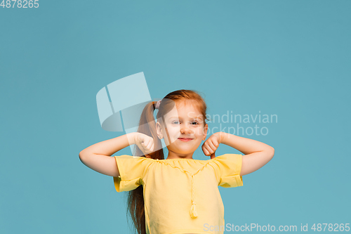 Image of Happy caucasian little girl isolated on blue studio background. Looks happy, cheerful, sincere. Copyspace. Childhood, education, emotions concept