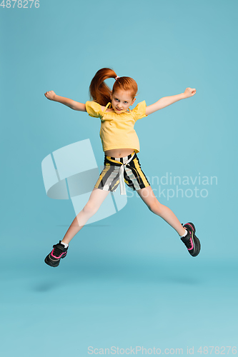 Image of Happy caucasian little girl isolated on blue studio background. Looks happy, cheerful, sincere. Copyspace. Childhood, education, emotions concept