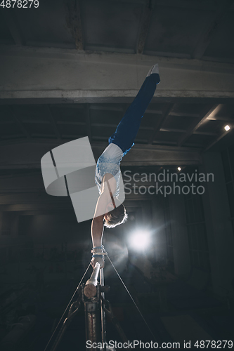 Image of Little male gymnast training in gym, flexible and active. Caucasian fit little boy, athlete in sportswear practicing in exercises for strength, balance.