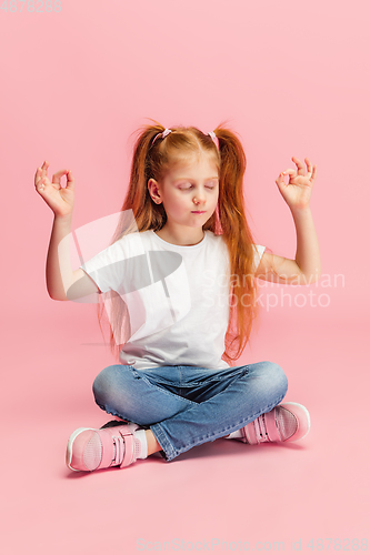 Image of Happy caucasian little girl isolated on pink studio background. Looks happy, cheerful, sincere. Copyspace. Childhood, education, emotions concept