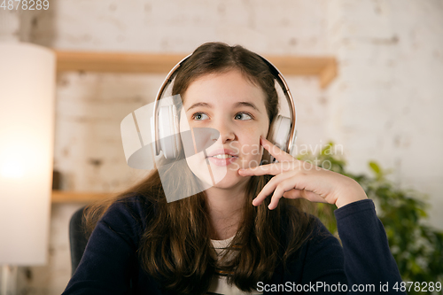 Image of Little girl wearing headphones during online education course, lesson, view of screen