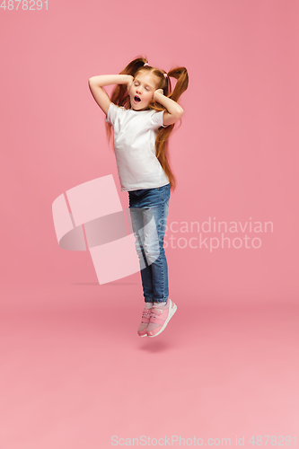 Image of Happy caucasian little girl isolated on pink studio background. Looks happy, cheerful, sincere. Copyspace. Childhood, education, emotions concept