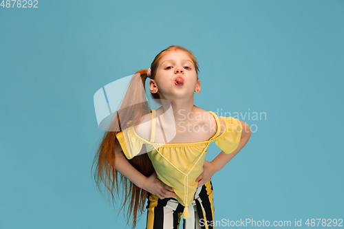 Image of Happy caucasian little girl isolated on blue studio background. Looks happy, cheerful, sincere. Copyspace. Childhood, education, emotions concept