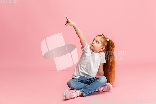 Image of Happy caucasian little girl isolated on pink studio background. Looks happy, cheerful, sincere. Copyspace. Childhood, education, emotions concept