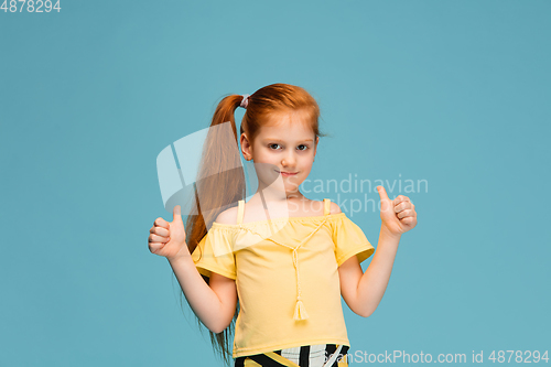 Image of Happy caucasian little girl isolated on blue studio background. Looks happy, cheerful, sincere. Copyspace. Childhood, education, emotions concept