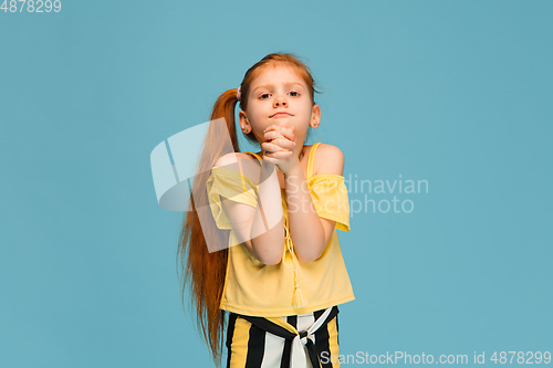 Image of Happy caucasian little girl isolated on blue studio background. Looks happy, cheerful, sincere. Copyspace. Childhood, education, emotions concept