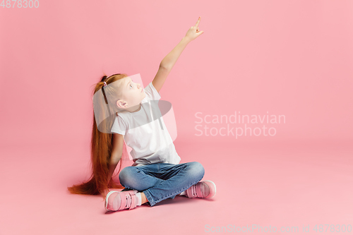 Image of Happy caucasian little girl isolated on pink studio background. Looks happy, cheerful, sincere. Copyspace. Childhood, education, emotions concept
