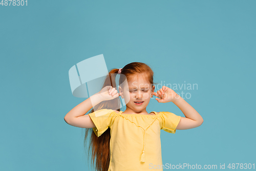 Image of Happy caucasian little girl isolated on blue studio background. Looks happy, cheerful, sincere. Copyspace. Childhood, education, emotions concept