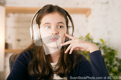 Image of Little girl wearing headphones during online education course, lesson, view of screen