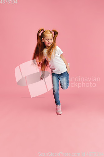 Image of Happy caucasian little girl isolated on pink studio background. Looks happy, cheerful, sincere. Copyspace. Childhood, education, emotions concept