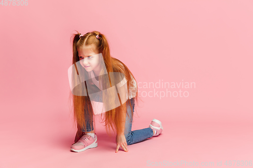 Image of Happy caucasian little girl isolated on pink studio background. Looks happy, cheerful, sincere. Copyspace. Childhood, education, emotions concept