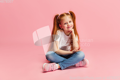 Image of Happy caucasian little girl isolated on pink studio background. Looks happy, cheerful, sincere. Copyspace. Childhood, education, emotions concept