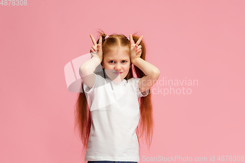 Image of Happy caucasian little girl isolated on pink studio background. Looks happy, cheerful, sincere. Copyspace. Childhood, education, emotions concept