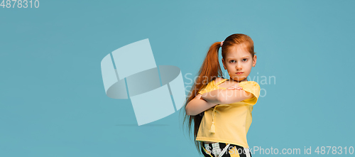 Image of Happy caucasian little girl isolated on blue studio background. Looks happy, cheerful, sincere. Copyspace. Childhood, education, emotions concept
