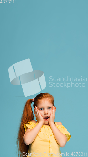 Image of Happy caucasian little girl isolated on blue studio background. Looks happy, cheerful, sincere. Copyspace. Childhood, education, emotions concept