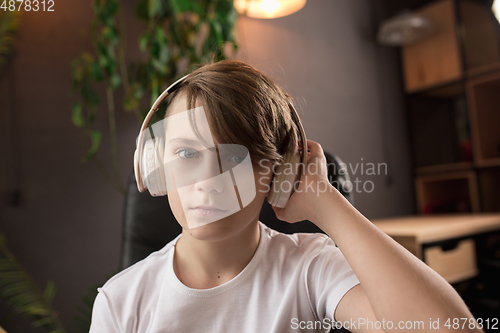 Image of Little boy wearing headphones during online education course, lesson, view of screen