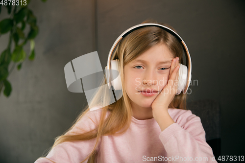 Image of Little girl wearing headphones during online education course, lesson, view of screen