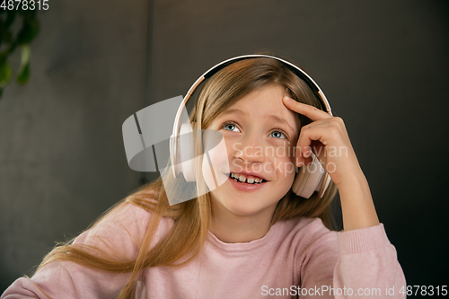 Image of Little girl wearing headphones during online education course, lesson, view of screen