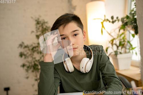 Image of Little boy wearing headphones during online education course, lesson, view of screen