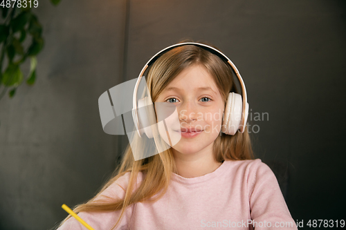 Image of Little girl wearing headphones during online education course, lesson, view of screen