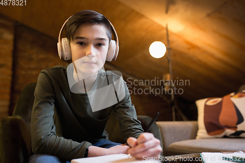 Image of Little boy wearing headphones during online education course, lesson, view of screen