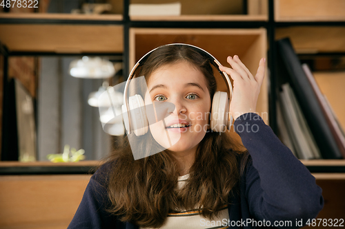 Image of Little girl wearing headphones during online education course, lesson, view of screen