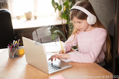 Image of Little girl studying by group video call, use video conference with teacher, listening to online course