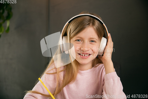 Image of Little girl wearing headphones during online education course, lesson, view of screen