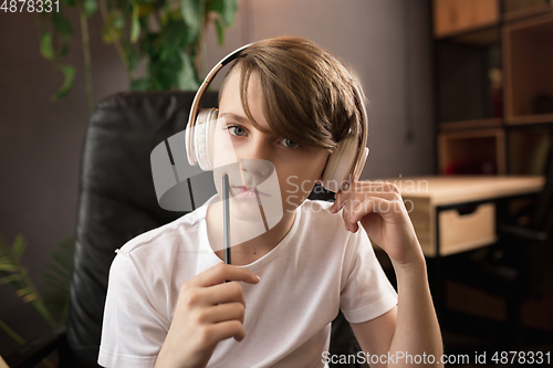 Image of Little boy wearing headphones during online education course, lesson, view of screen
