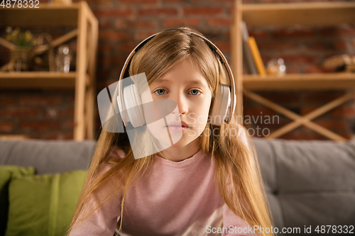 Image of Little girl wearing headphones during online education course, lesson, view of screen