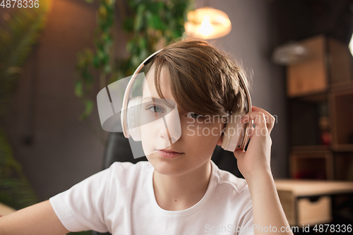 Image of Little boy wearing headphones during online education course, lesson, view of screen