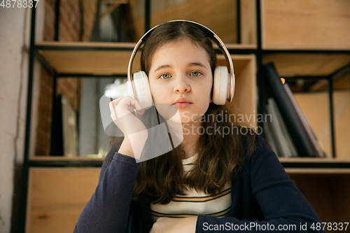 Image of Little girl wearing headphones during online education course, lesson, view of screen