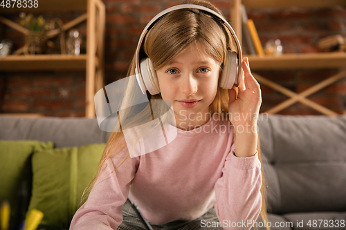 Image of Little girl wearing headphones during online education course, lesson, view of screen