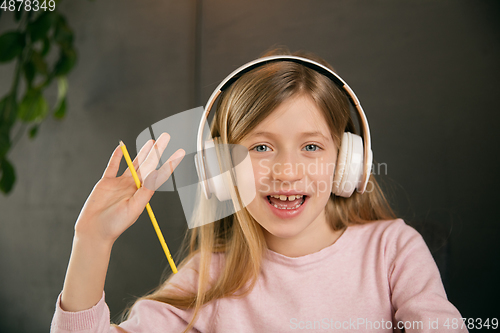 Image of Little girl wearing headphones during online education course, lesson, view of screen