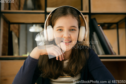 Image of Little girl wearing headphones during online education course, lesson, view of screen