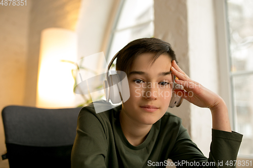 Image of Little boy wearing headphones during online education course, lesson, view of screen