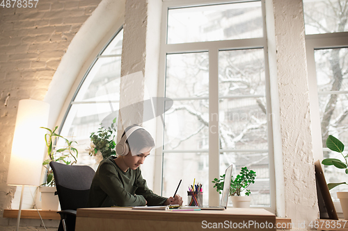 Image of Little boy wearing headphones during online education course, lesson, view of screen