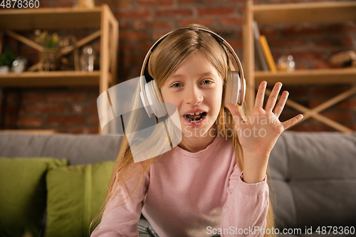 Image of Little girl wearing headphones during online education course, lesson, view of screen