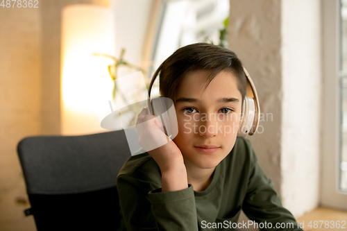 Image of Little boy wearing headphones during online education course, lesson, view of screen