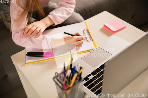 Image of Close up hands of girl writing during group video call, use video conference with teacher, listening to online course