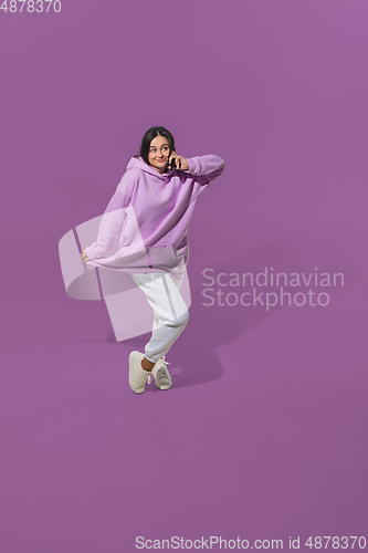 Image of High angle view of young woman on purple studio background. Girl in motion or movement. Human emotions and facial expressions concept