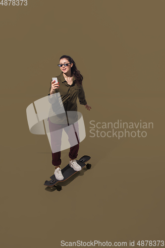 Image of High angle view of young woman on brown studio background. Girl in motion or movement. Human emotions and facial expressions concept