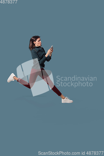 Image of High angle view of young woman on blue studio background. Girl in motion or movement. Human emotions and facial expressions concept