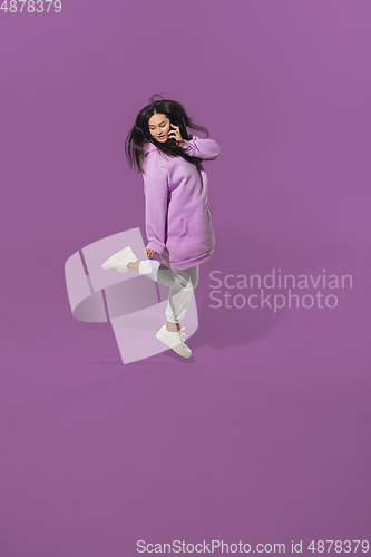 Image of High angle view of young woman on purple studio background. Girl in motion or movement. Human emotions and facial expressions concept