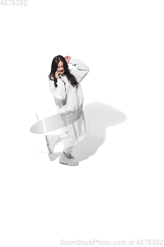 Image of High angle view of young woman on white studio background. Girl in motion or movement. Human emotions and facial expressions concept